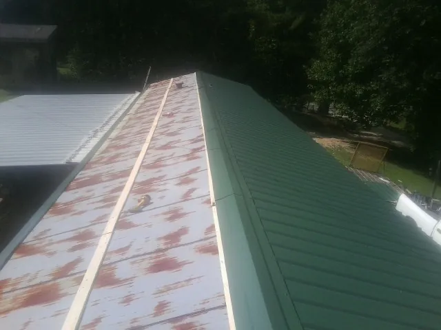Old rusted panels beside newly installed green metal roofing — Wind Damage Roof Repair by Roofing Brothers in Kensington