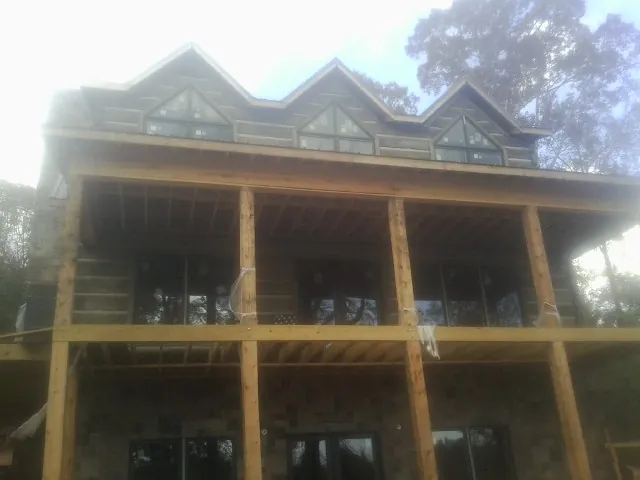 Dormers and porch framing on a large log home under construction — Roof Coating work by our crew in Kensington
