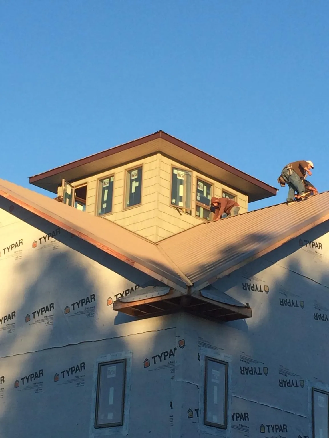 Roofers working around a rooftop cupola on a new metal roof at sunset — Roof Waterproofing in Kensington by Roofing Brothers